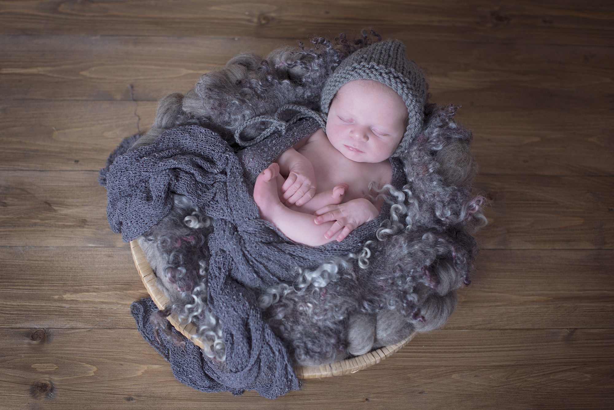 baby snuggles in basket by newborn photographer Reading