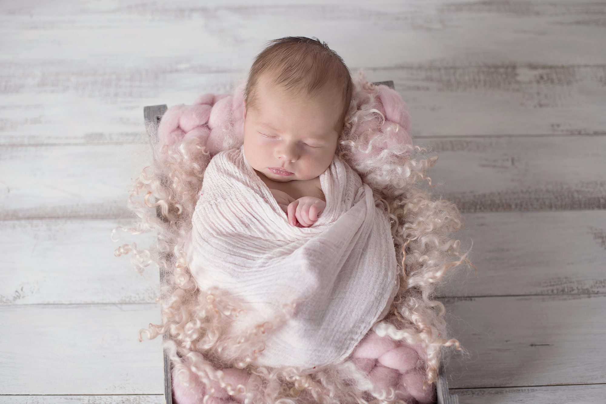 baby asleep in pink fluffy crate during newborn photoshoot Wokingham