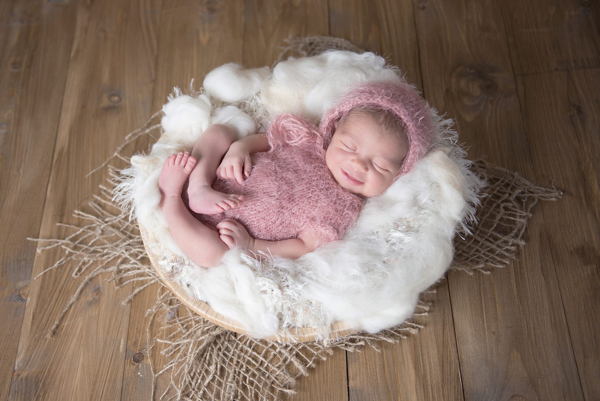 baby girl in pink smiling in newborn photography session Wokingham