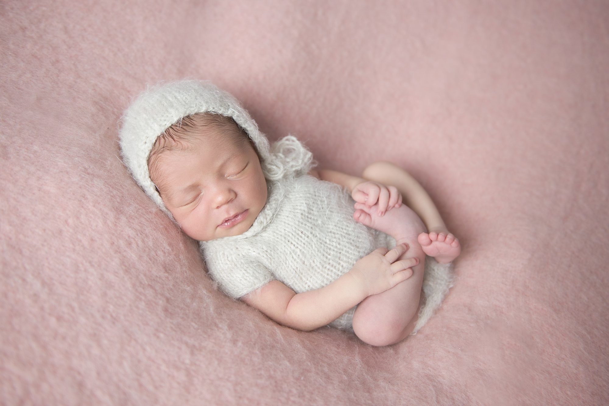 baby asleep in cream romper on pink blanket taken by newborn photographer Maidenhead