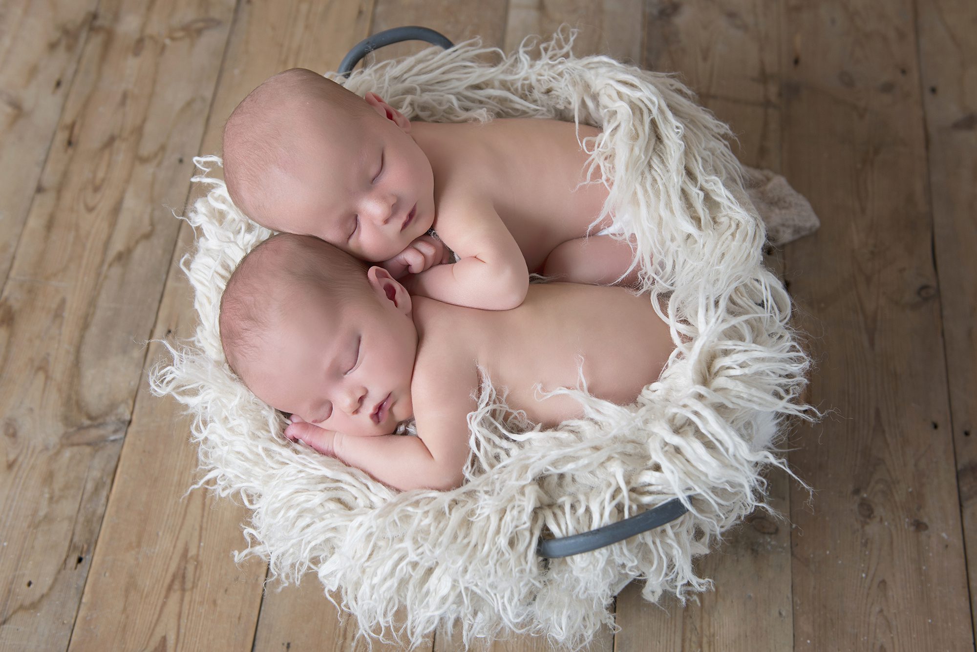 twin babies snuggled together on cream fur blanket in photography shoot Maidenhead