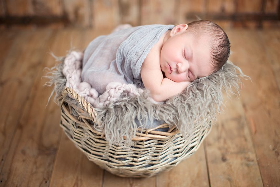 sleeping newborn baby in basket by photographer in Wokingham
