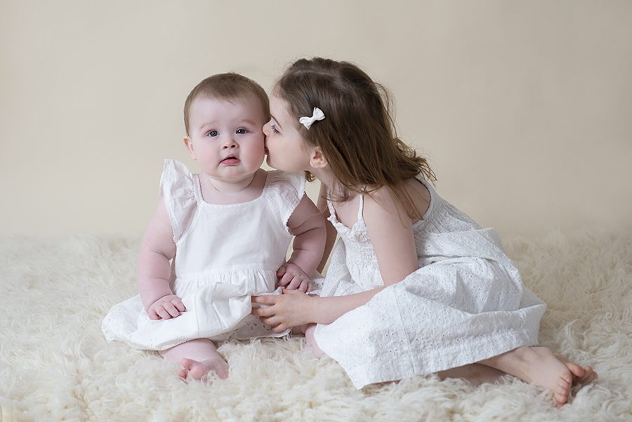 kissing little sisters cheek, photo session, Twyford, Reading, Berkshire. Baby photography